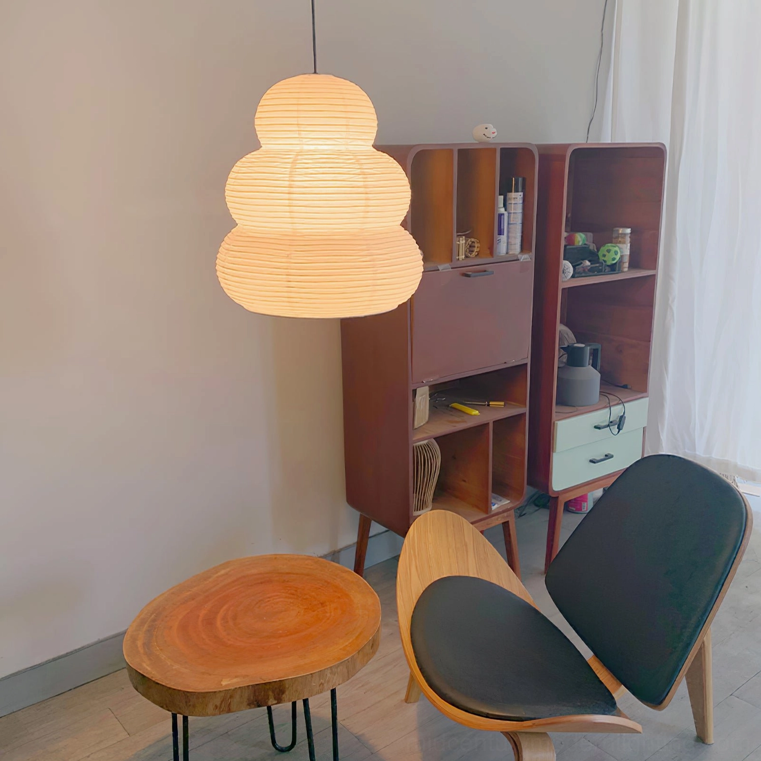 Washi 24N pendant light illuminated in mid-century modern home lounge, warm glowing ambient lighting above wooden furniture