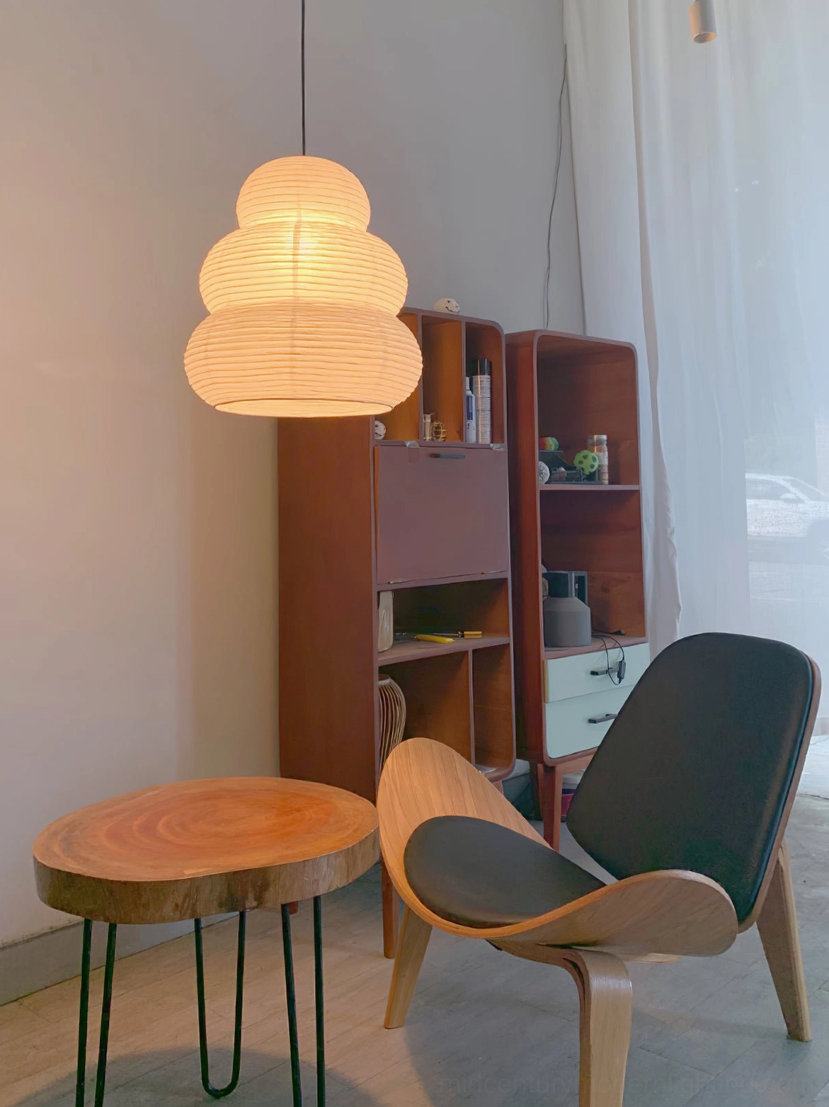Washi 24N pendant light illuminated in mid-century modern lounge with matching wooden furniture and warm ambience