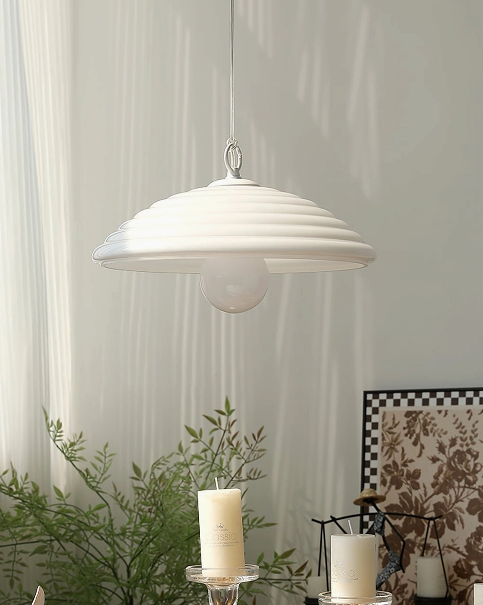Wave glass pendant light bright white sleek ribbed silhouette hanging in room with sheer curtains and candle decor