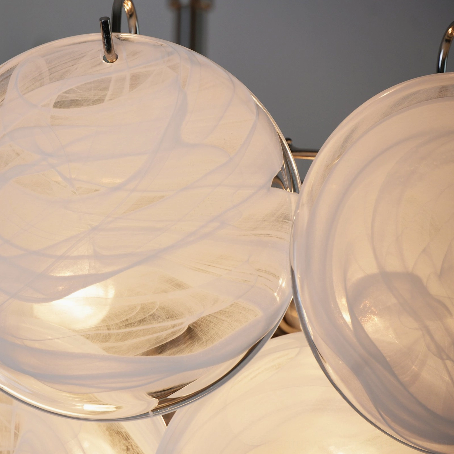 White glass disc chandelier with round discs arranged in conical layers and silver metal hanging chain, interior design showcase