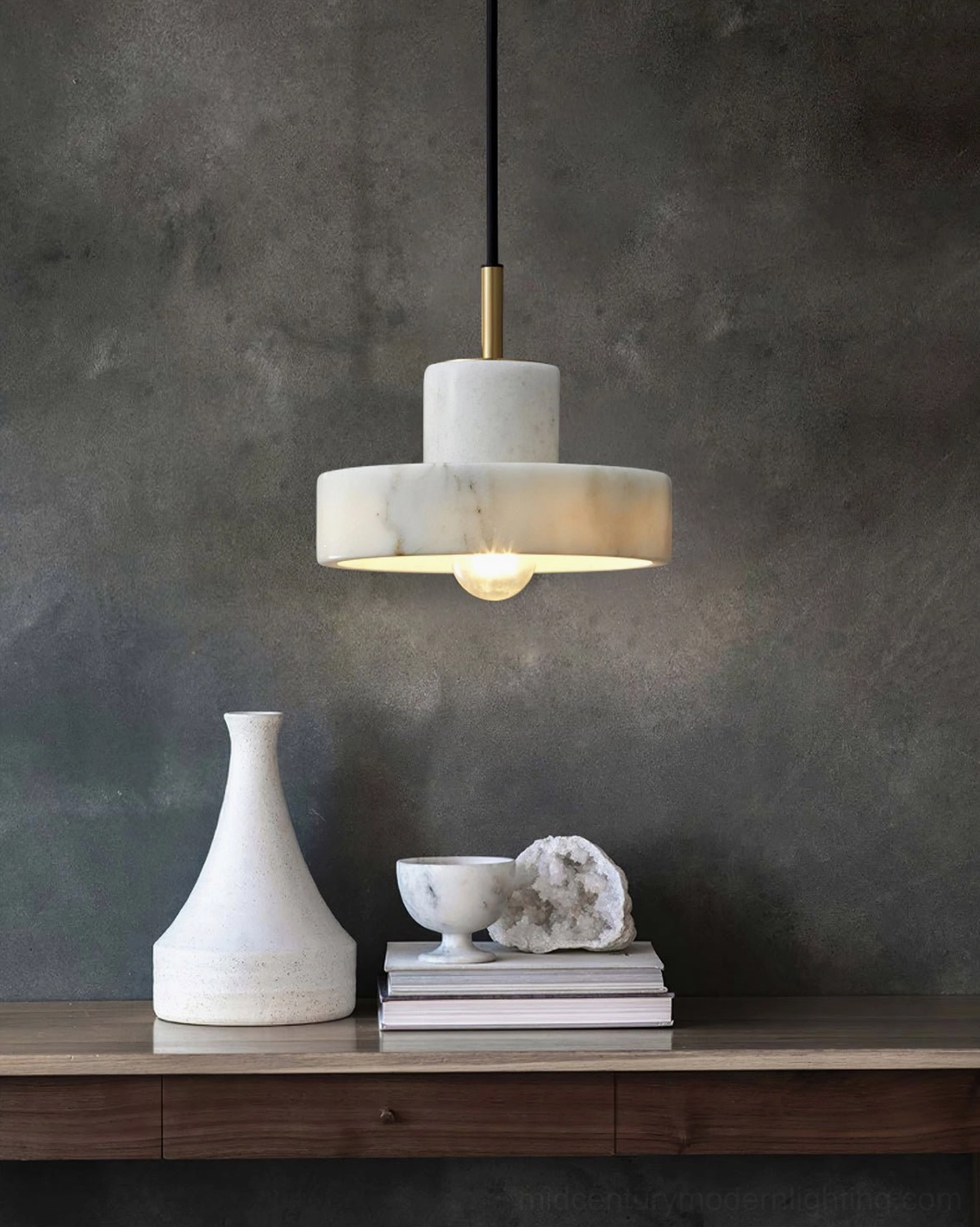 White marble pendant light suspended above console table with dark textured wall and tabletop decor