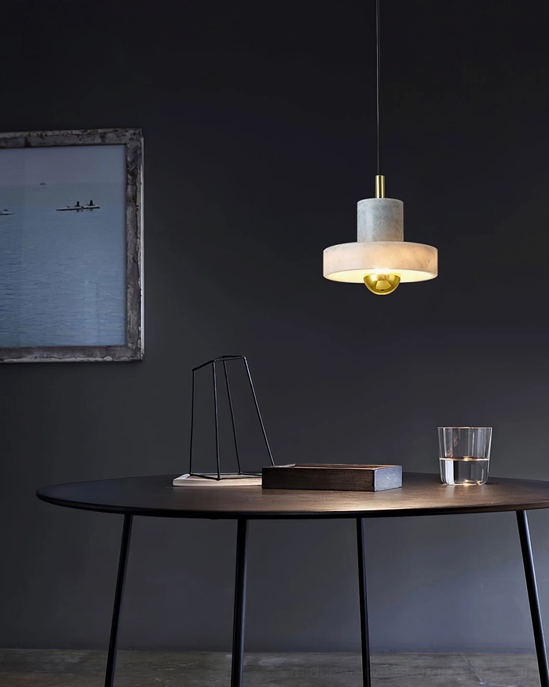 White marble pendant light hung above round black dining table in modern dining space with navy wall
