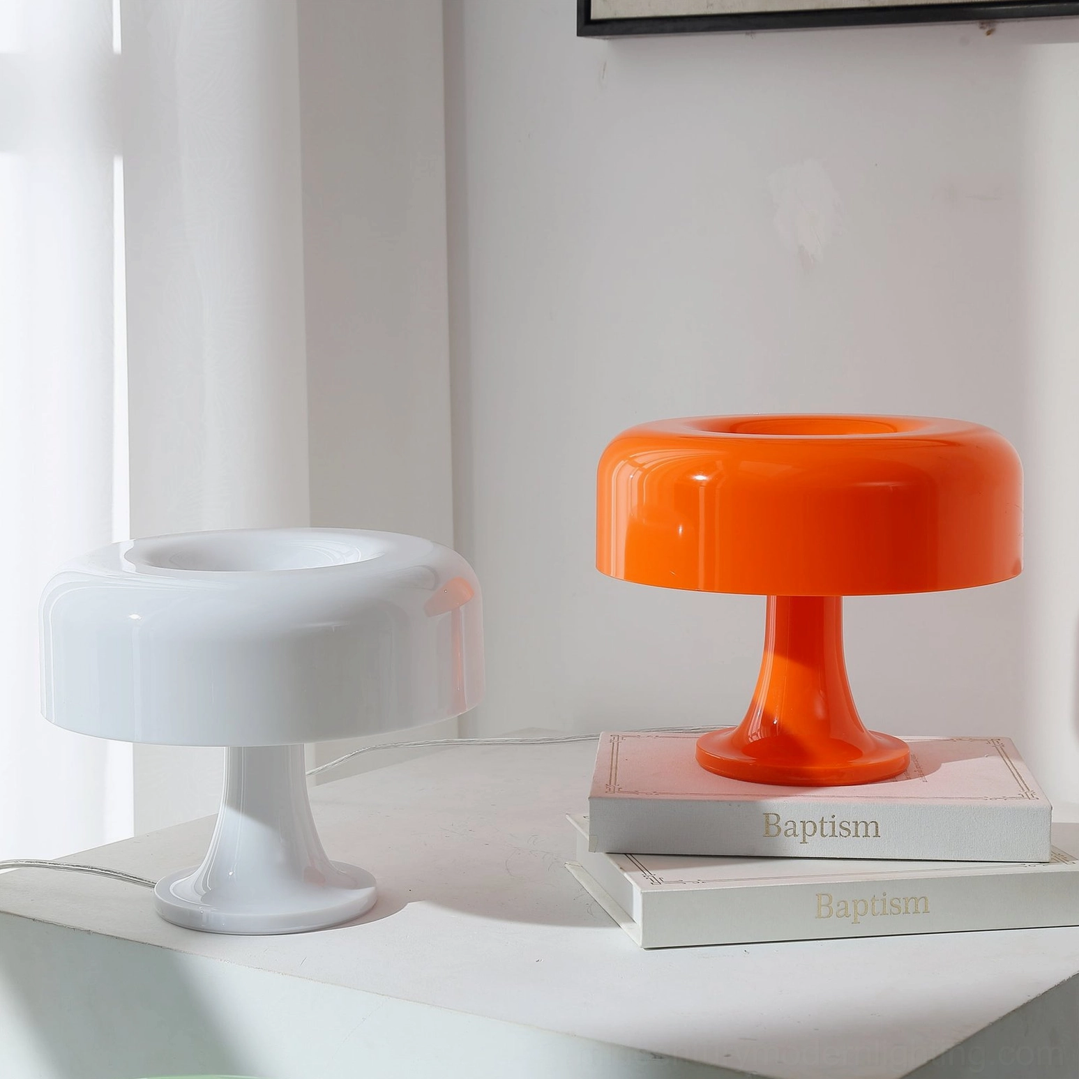 White and orange mushroom table lamps side by side on stacked books, showing acrylic translucent finish comparison