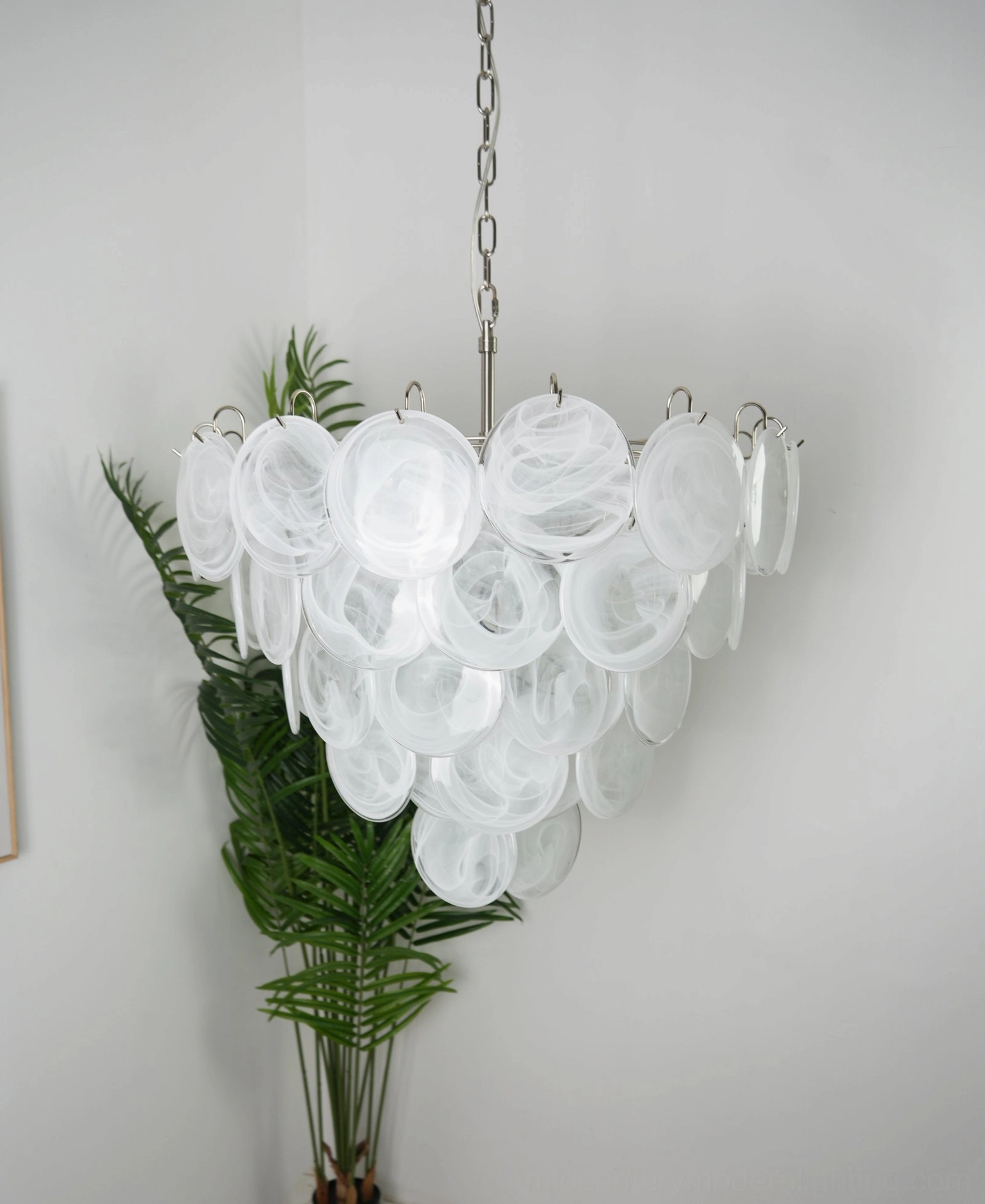 White translucent disc chandelier with reflective glass surfaces and tiered conical design in modern home setting