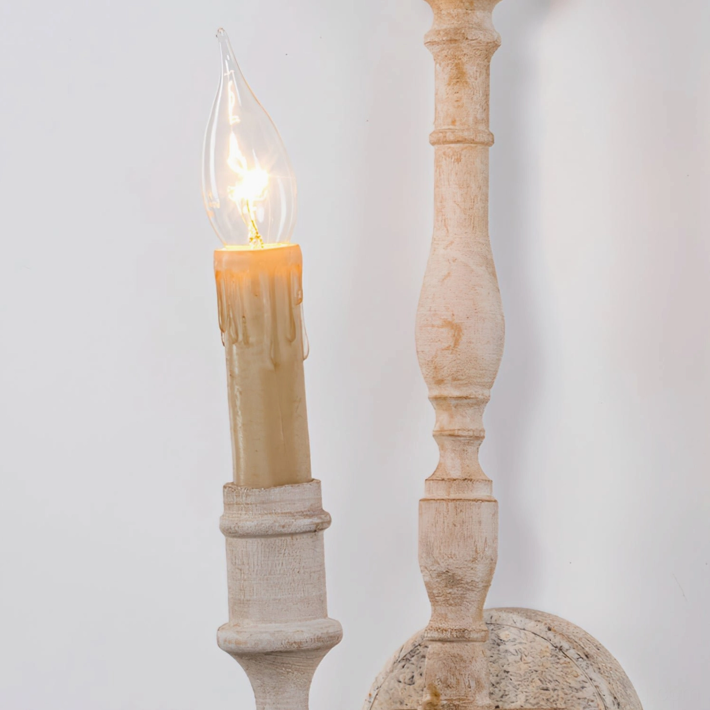 Candlestick-style wall lamp with dripping candle simulation in off-white weathered finish