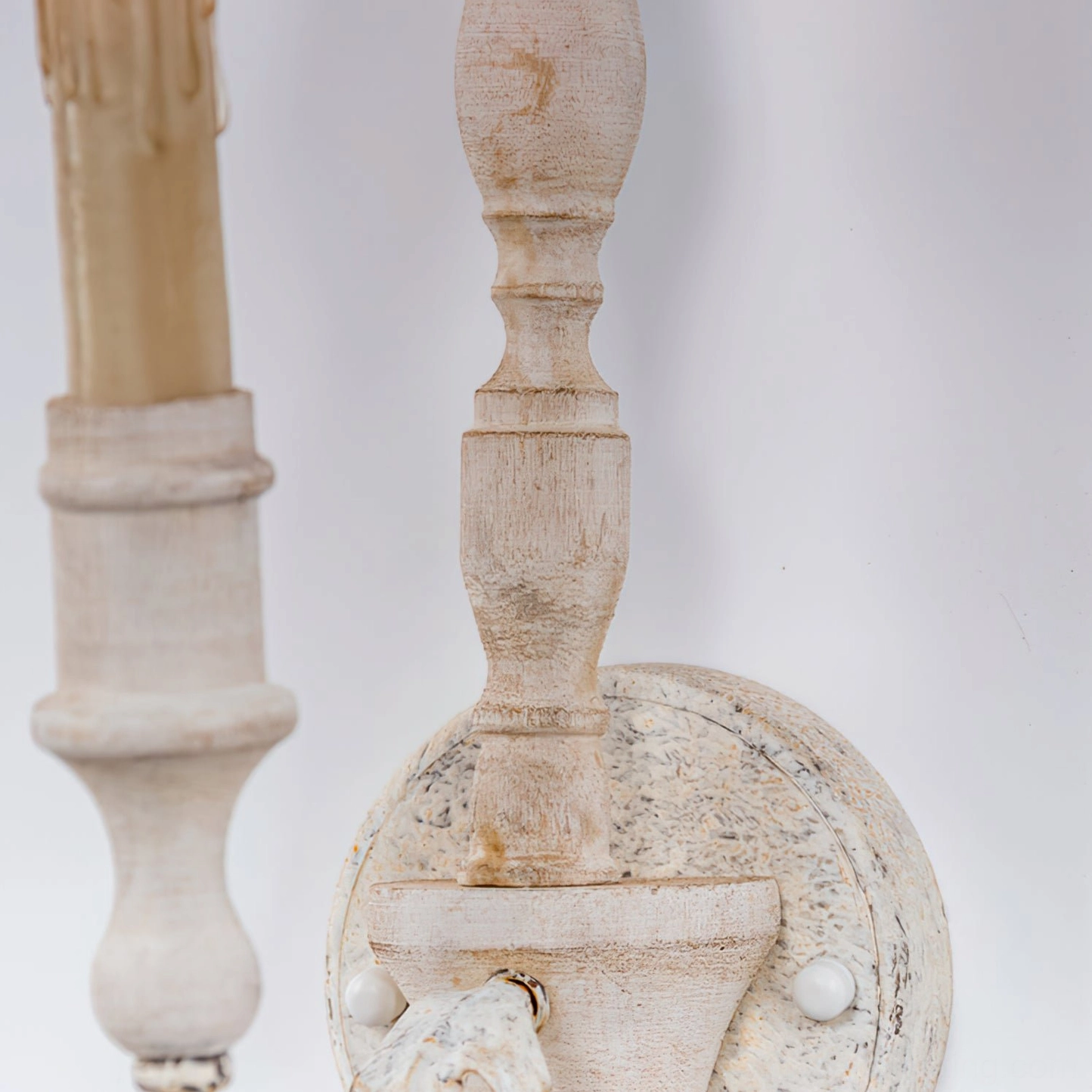 Close-up of off-white distressed wall sconce with turned wooden spindle details