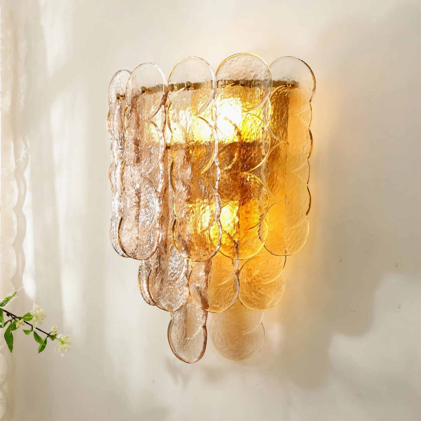 Wide-profile tiered glass wall sconce in modern interior with sheer curtains