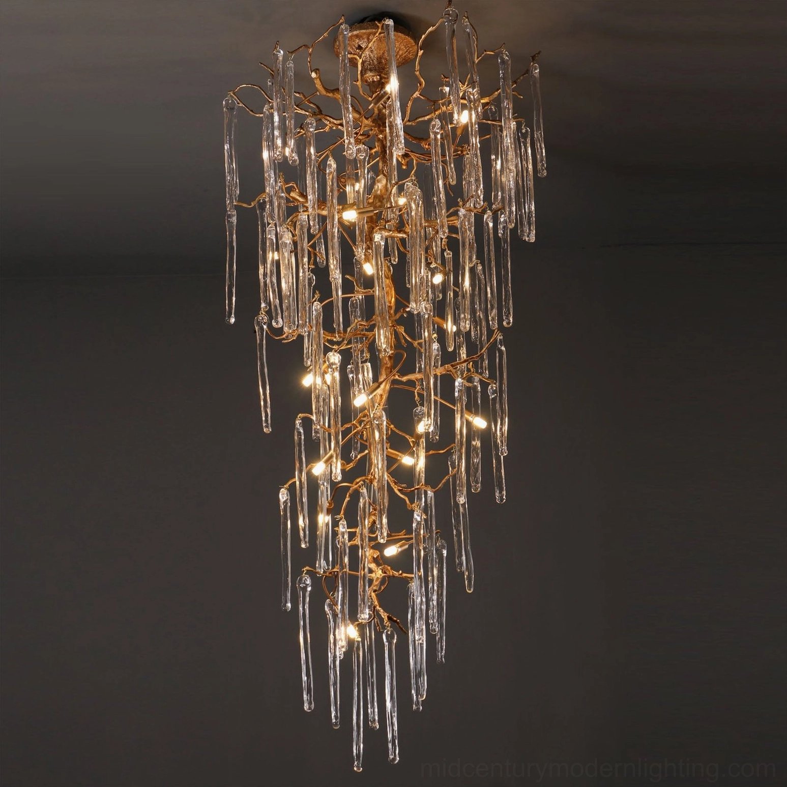 Organic branch glass chandelier with warm gold frame, dark studio background, cascading crystal detail