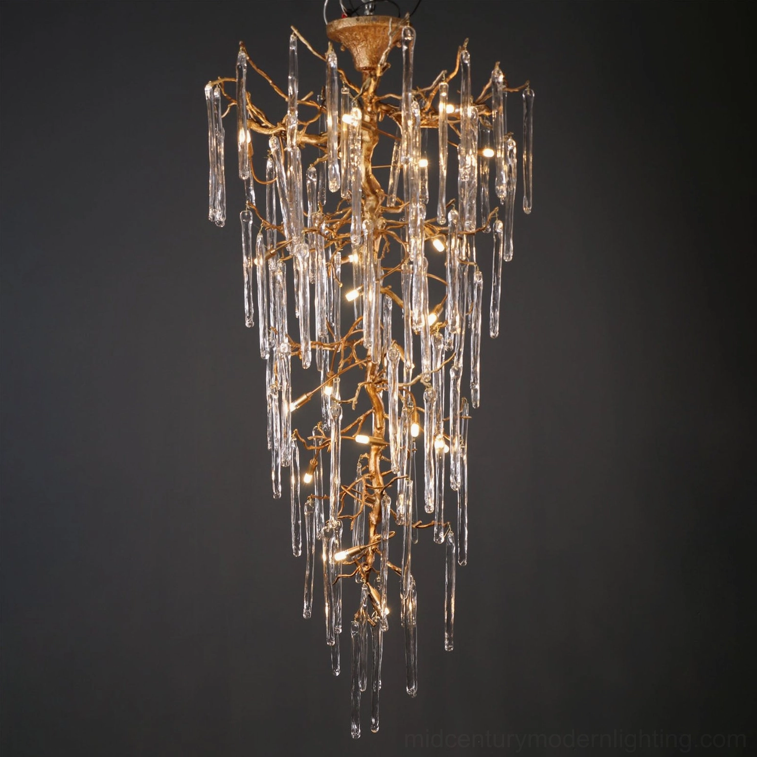Modern glass chandelier suspended in two-story entryway, warm ambient light through glass drops