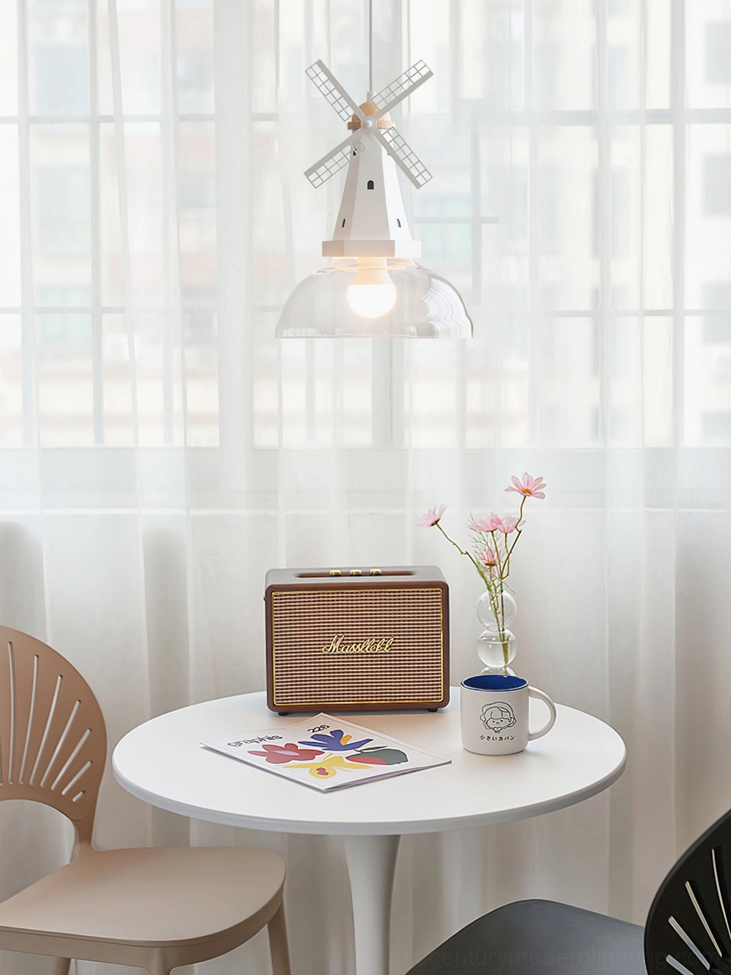 Windmill pendant installed above small dining table with round shape and retro radio in minimalist apartment