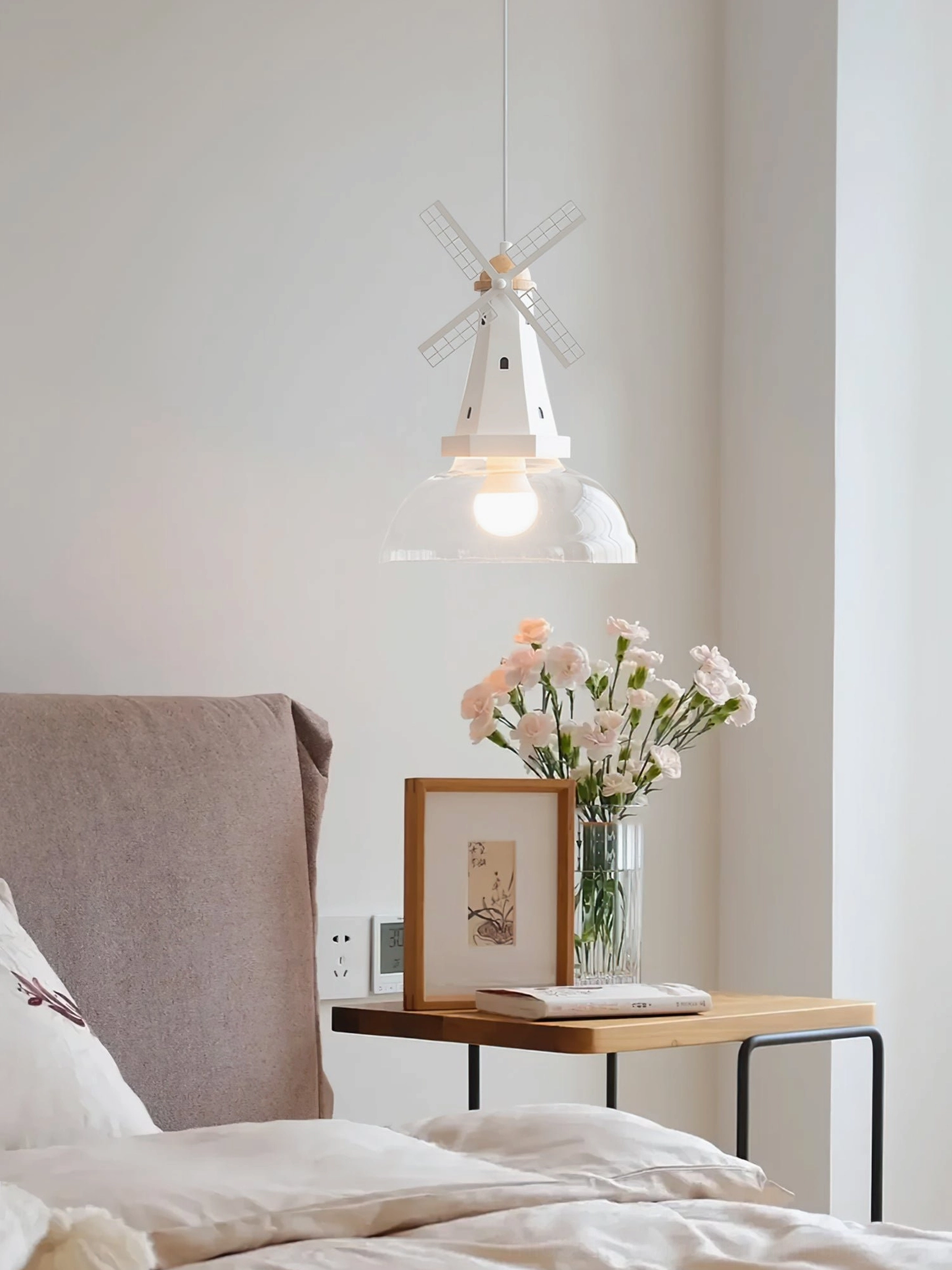 Windmill pendant hanging in cozy nordic bedroom with matching bedside table and floral decor