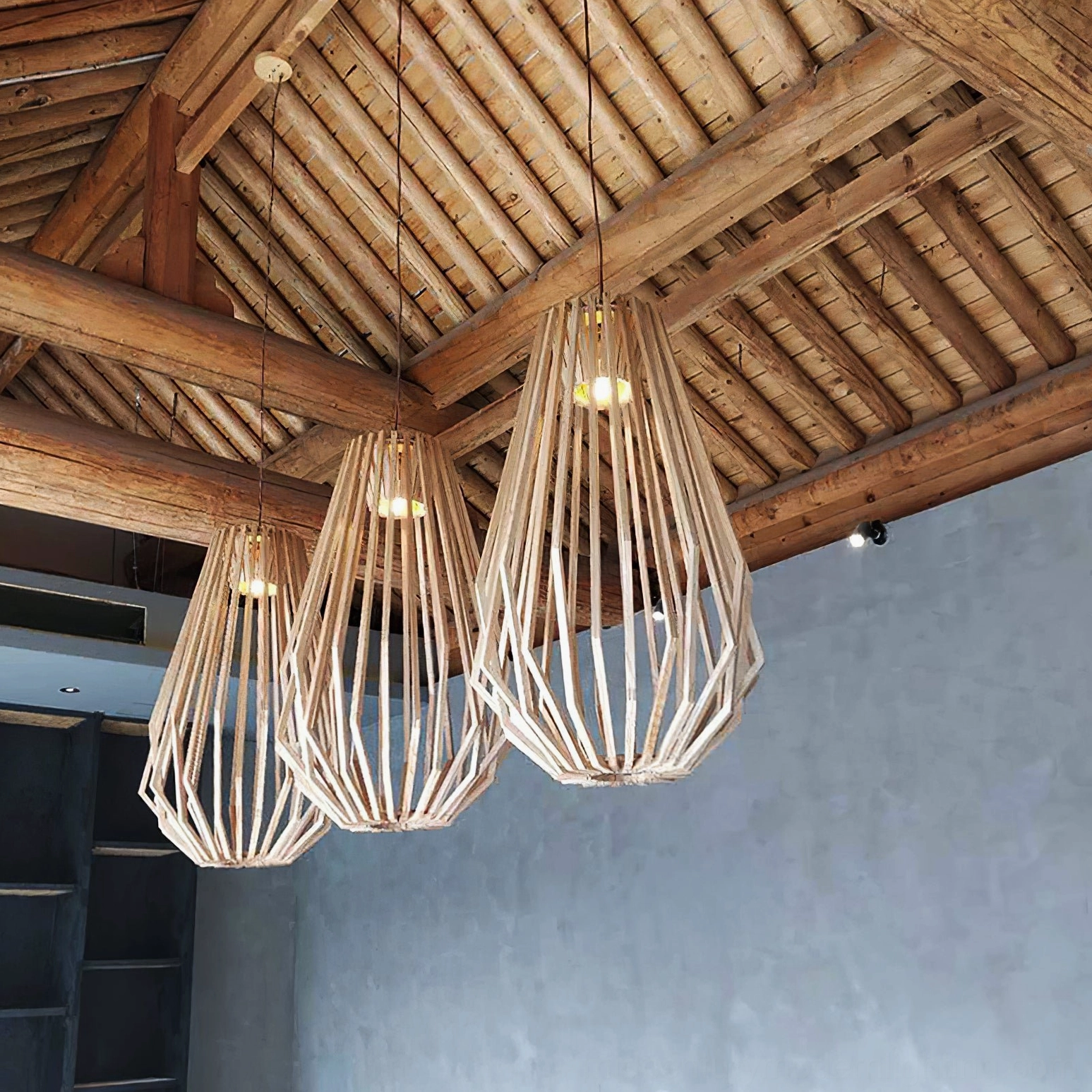 Three wood slat cage pendant lights suspended in traditional restaurant with wooden beams creating warm ambient farmhouse lighting