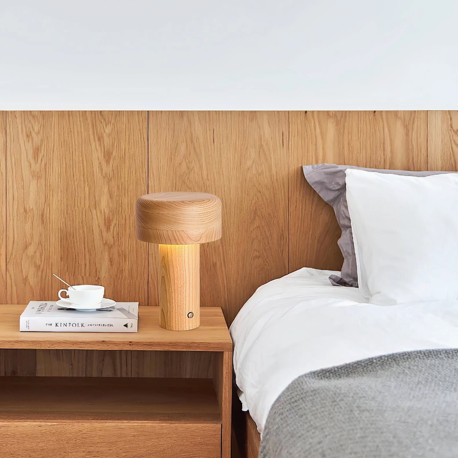 Natural ash wood lamp creating warm light on master bedroom bedside with coffee and bedding