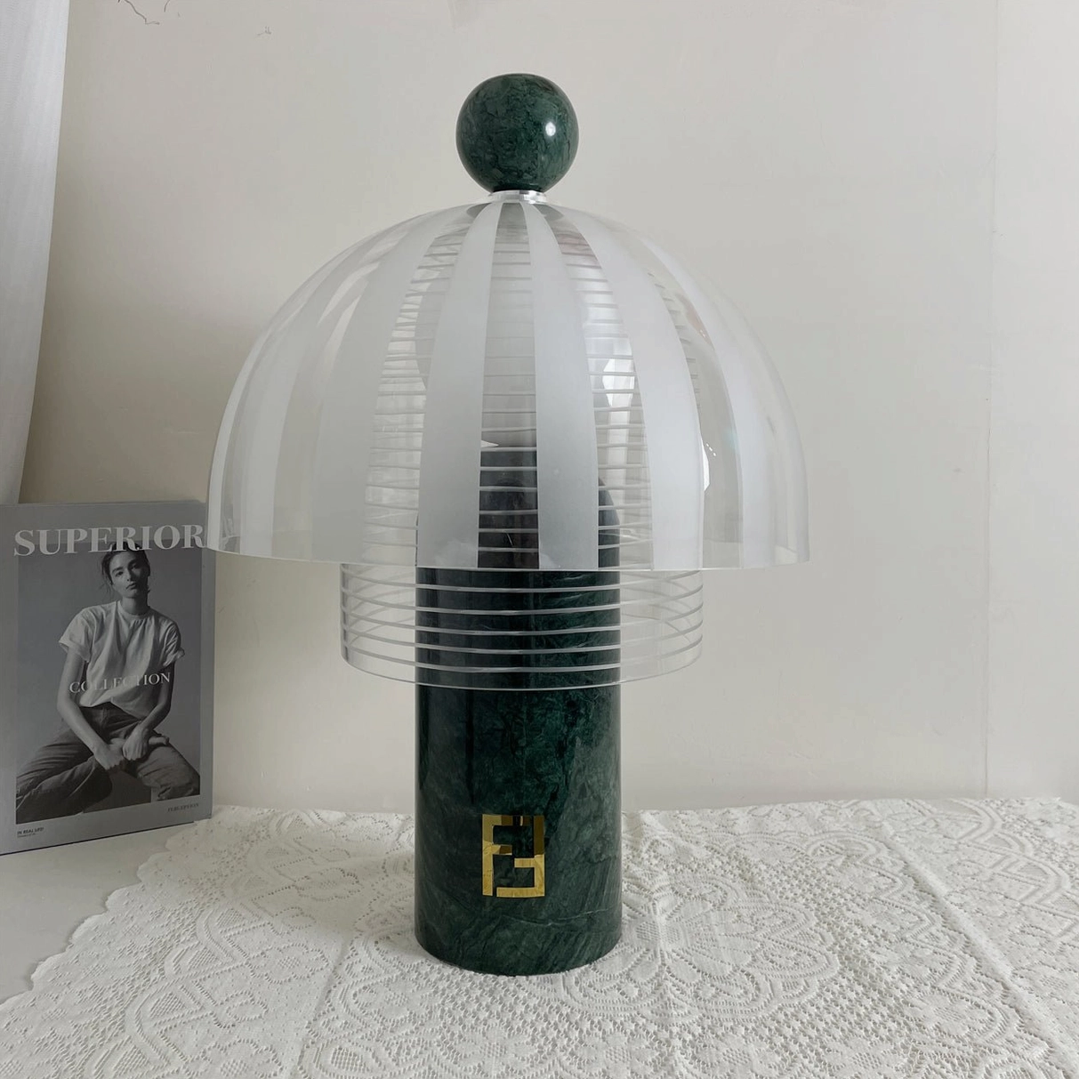 Unlit Yasuke table lamp front flat view on lace tablecloth with fashion magazine backdrop