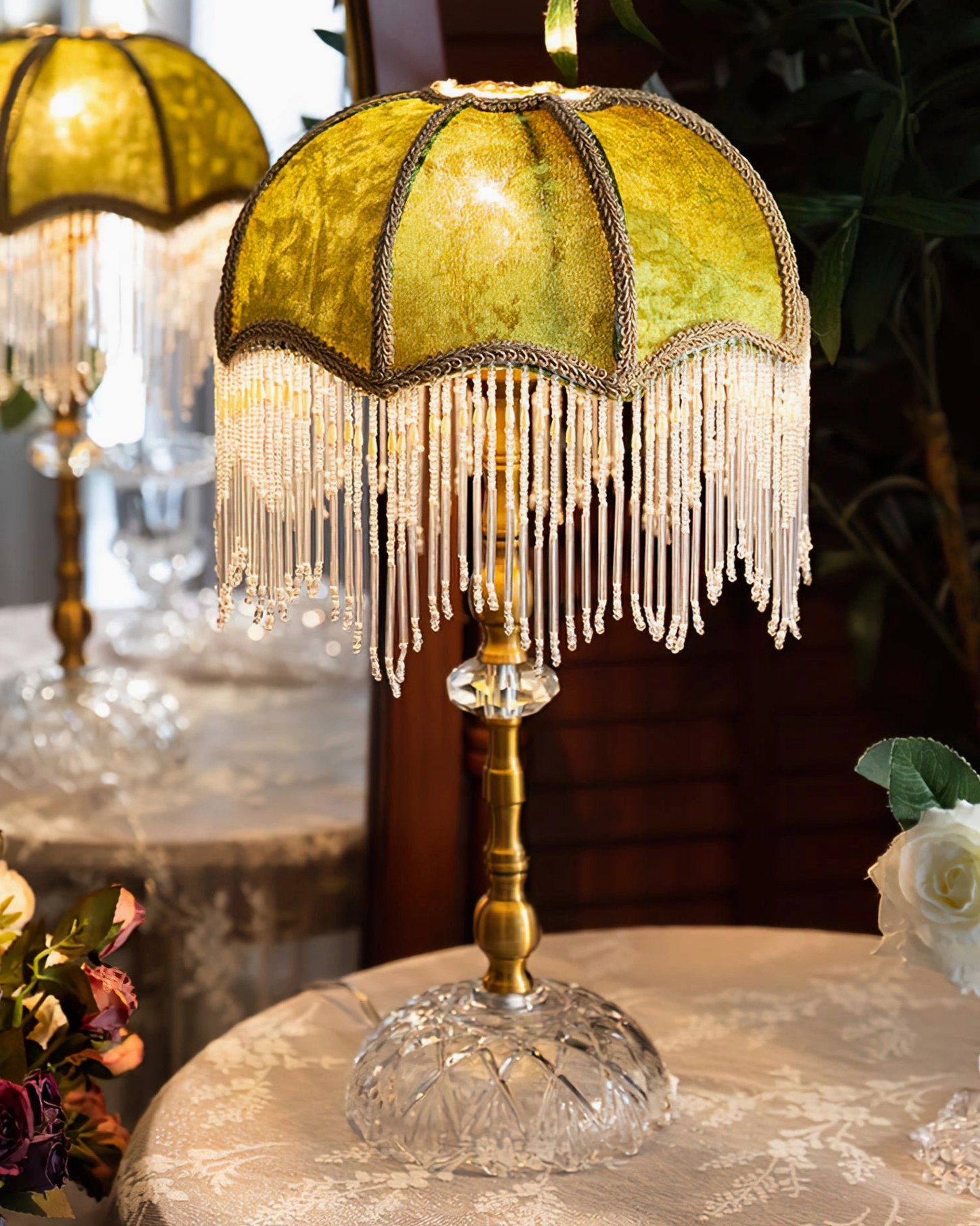 Yellow fringed table lamp close-up on lace-covered vintage table with warm glowing shade