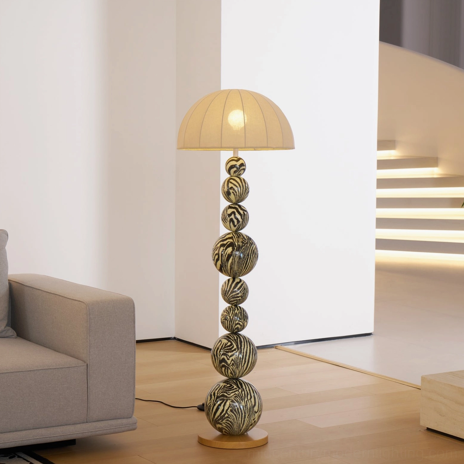 Contemporary zebra striped floor lamp in modern entryway with illuminated staircase and cream shade detail