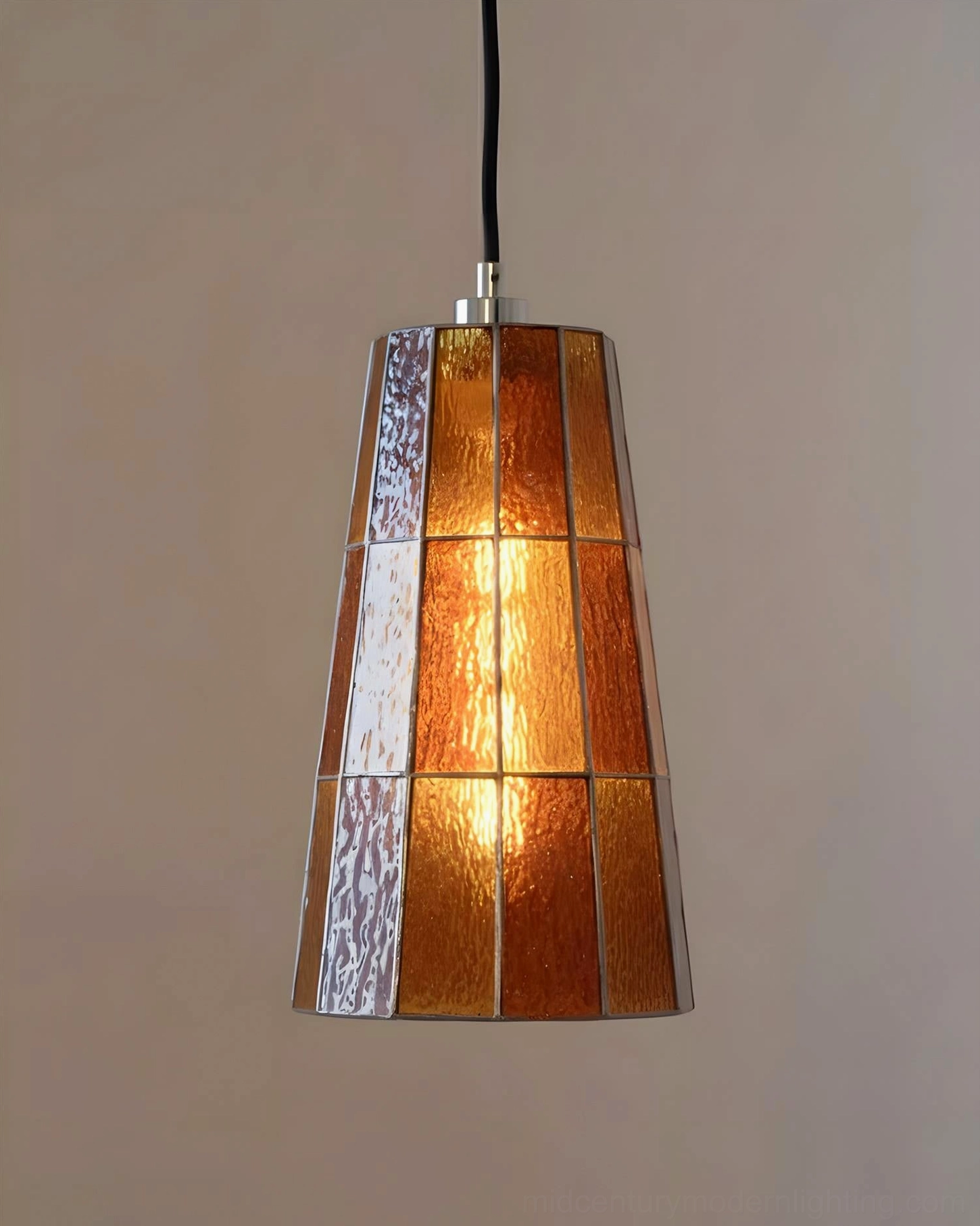 Zola geometric glass pendant lamp with illuminated amber tapered shade, frontal close-up view