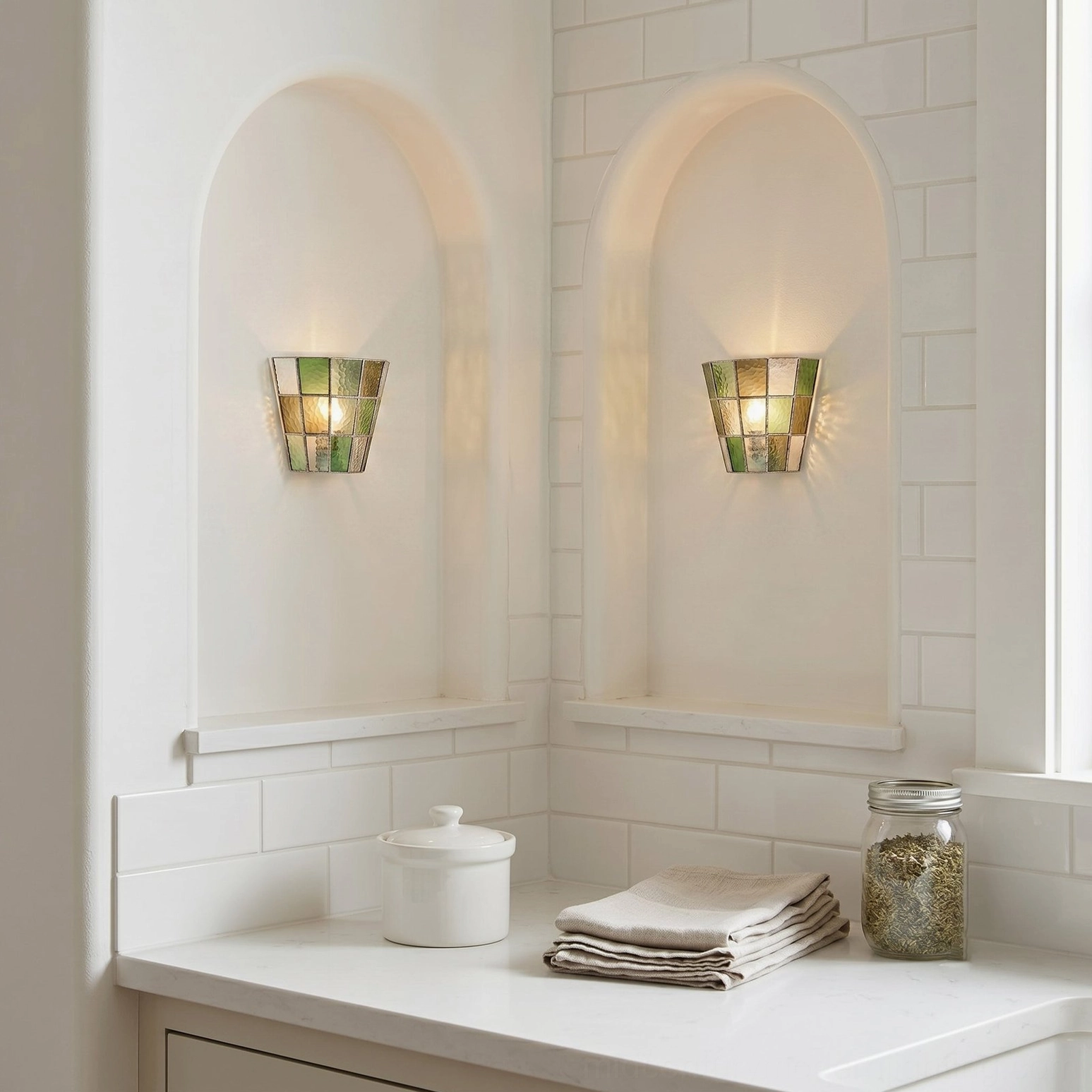 Pair of Zola muted green stained glass sconces installed in white subway tile bathroom niches